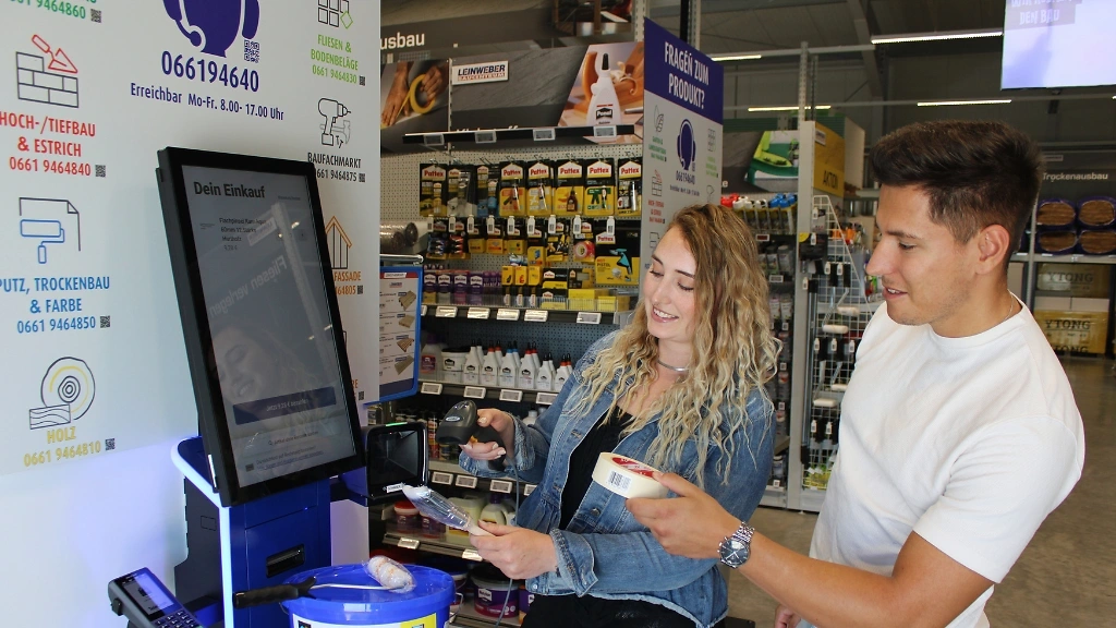 2 Personen scannen Ware am Selbstscan Terminal ab